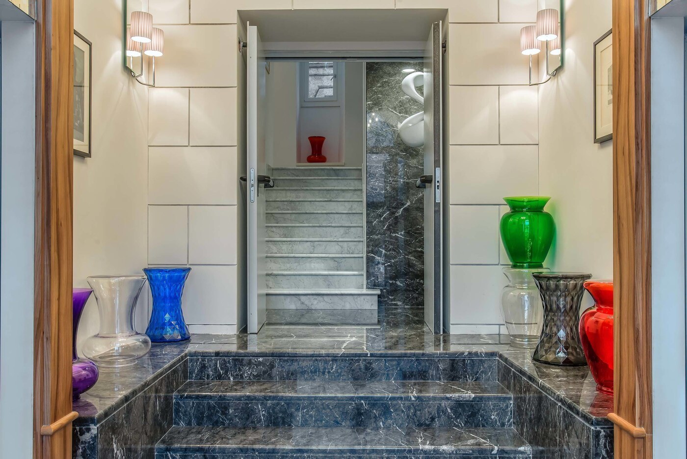 A marble staircase leading to a room with a window, a red vase, and a green vase on the landing. - Damaso Hotel (Rome)